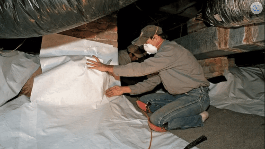 A crawlspace being sealed to prevent moisture infiltration and improve energy efficiency, showing the installation of polyethylene sheeting on the floor.